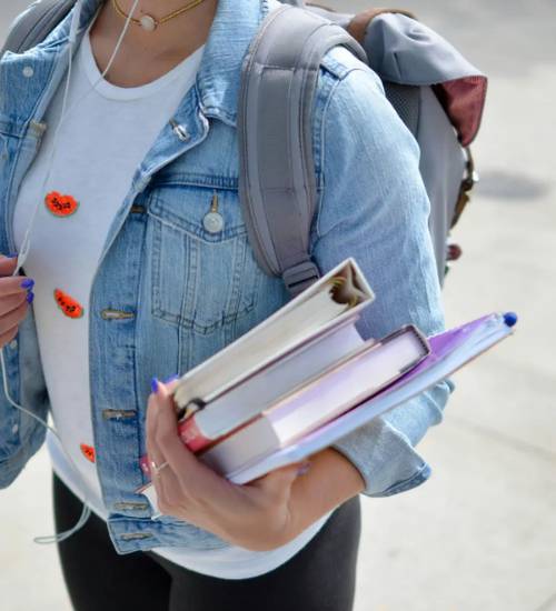 Estudiante llevando libros, que representa los cursos grupales de GRE y GMAT, así como las clases particulares de GRE y GMAT ofrecidas por el Brujo Method.
